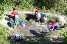 women wash clothes in old water source