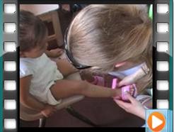 A missioner helps a child at the malnutrition center try some new shoes.