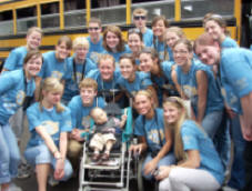 students pose with Illich at the airport