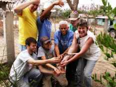 Corey Adair, Fr. Tigges, Caitlin Ascherl, Reynario, Luciano, Thomas Henrich, & Carolyn Bickford celebrate with water in Moya